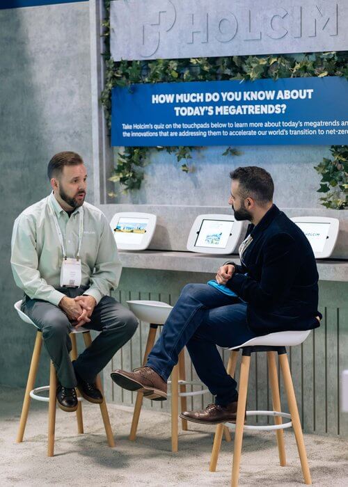 2 men talking at Holcim table chatting